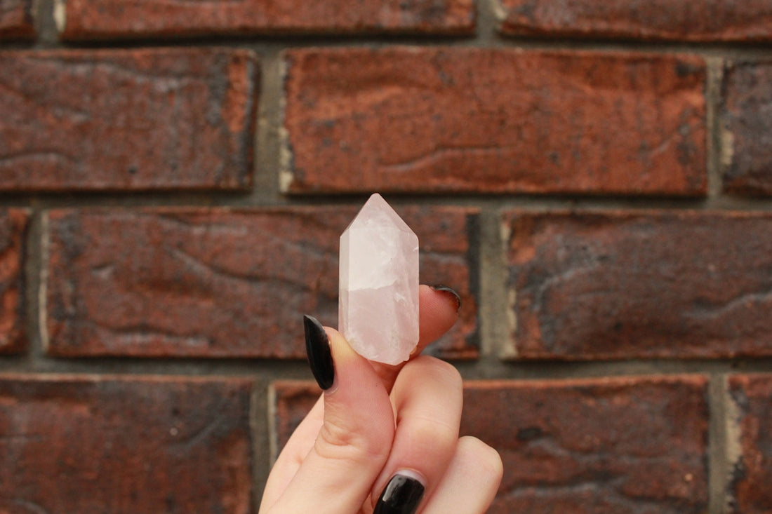 a person holding a piece of crystal in front of a brick wall