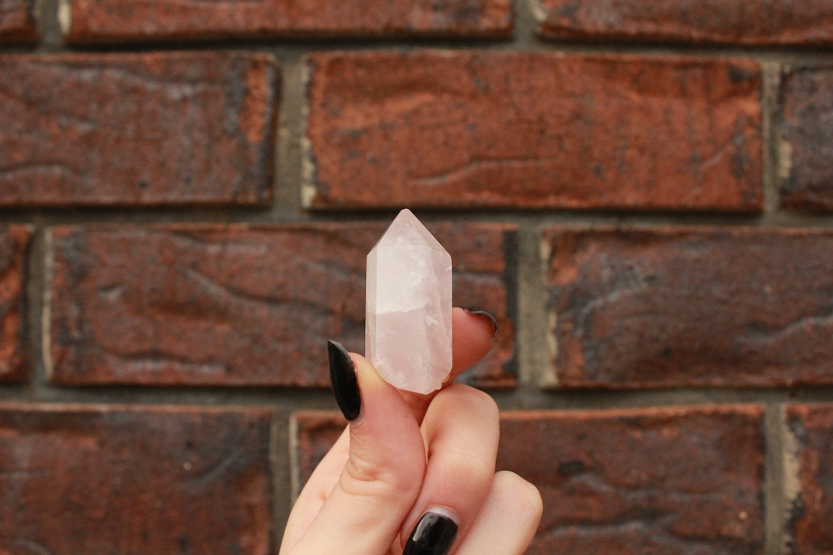 a person holding a piece of crystal in front of a brick wall